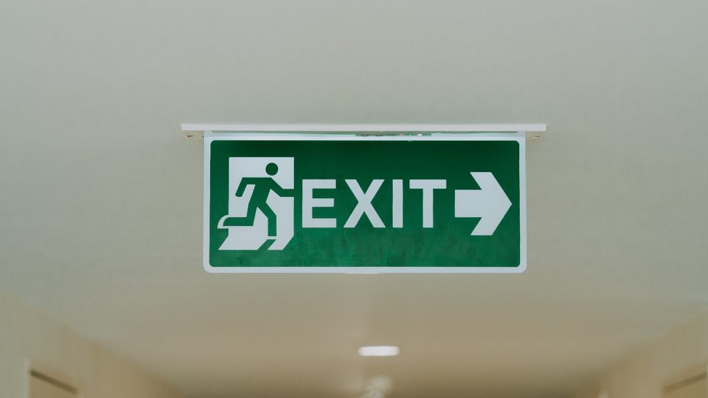 A green fire escape sign on the ceiling, pointing to the right