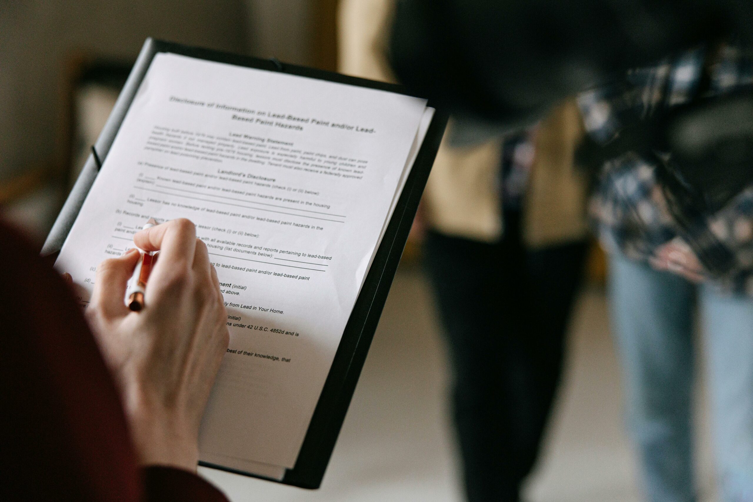 a person's hand holding a pen writing on a fire extinguisher inspection checklist in a workplace